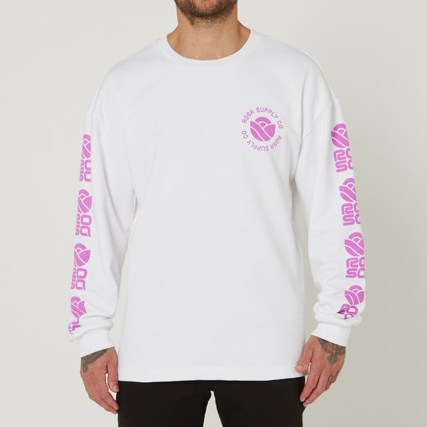 A person wearing a white long sleeve sweater with pink text and logo branding on the chest and sleeves.